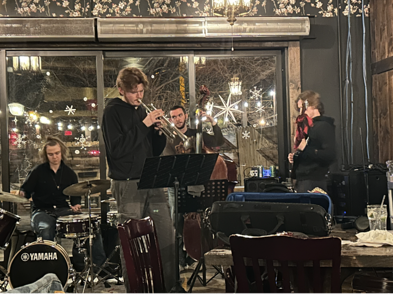 Students play instruments at jazz jam. Trumpet, stand-up bass, drum kit and guitar.